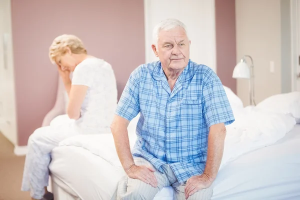 Tensed pareja de ancianos sentado en la cama — Foto de Stock