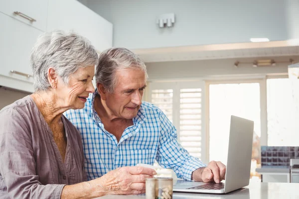 Senior couple with pills using laptop — Stock Photo, Image