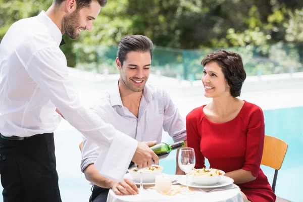 Serveur servant vin rouge à couple — Photo