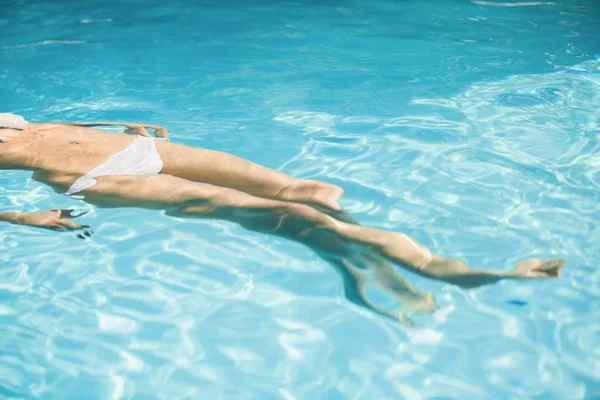 Жінка в білому бікіні плаває в басейні — стокове фото