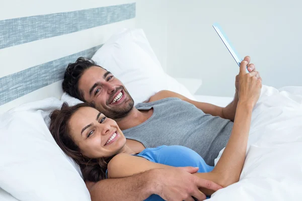 Casal com tablet enquanto deitado na cama — Fotografia de Stock