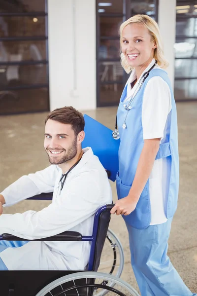 Doctor on wheelchair with female colleague — Stock Photo, Image