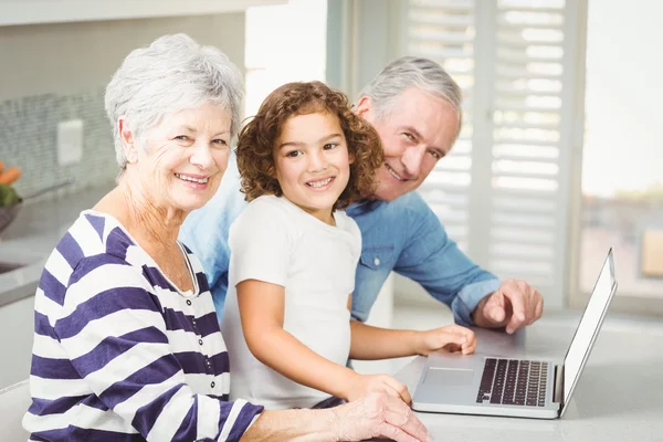 Portret van gelukkig meisje met grootouders met behulp van laptop — Stockfoto