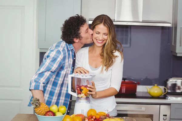Мужчина целует женщину, готовит сок — стоковое фото