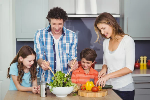 Pais e crianças preparando salada de legumes — Fotografia de Stock