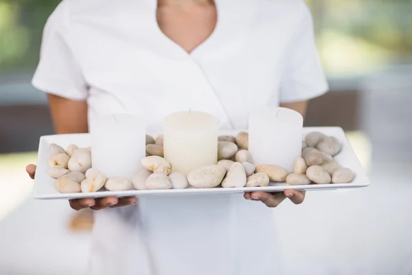 Masseur hält Tablett mit Kieselsteinen und Kerzen — Stockfoto