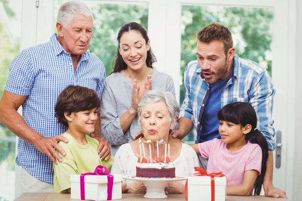 Granny blowing birthday candles with family — Stock Photo, Image