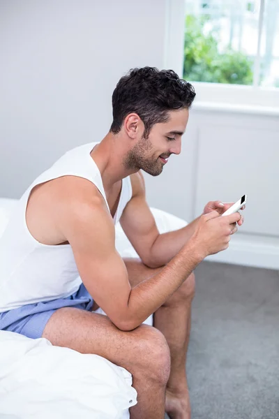 Человек с помощью мобильного телефона на кровати — стоковое фото