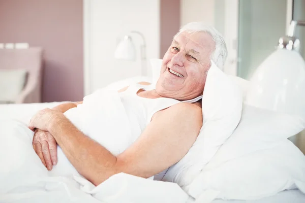Porträt eines fröhlichen Seniors, der es sich auf dem Bett gemütlich macht — Stockfoto