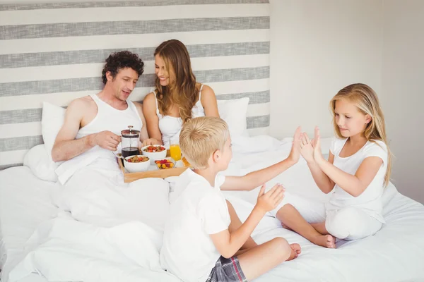 Speelse broers en zussen met ouders op bed — Stockfoto