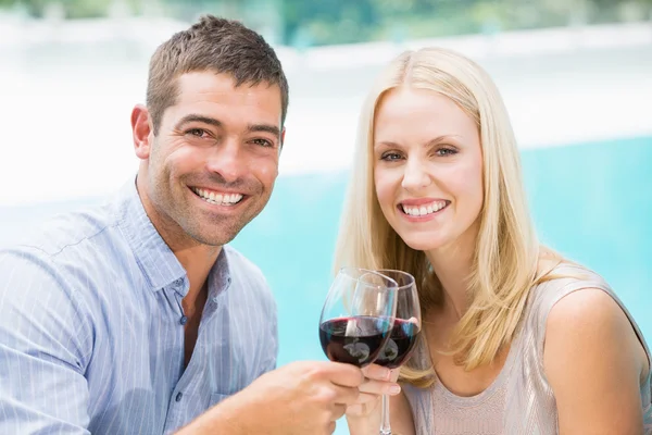 Couple toasting red wine while sitting by sw — Stock Photo, Image