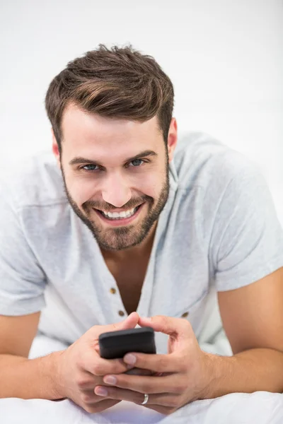 Uomo che utilizza il telefono cellulare sul letto — Foto Stock