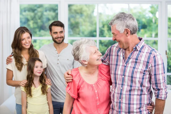 Grandparents embracing and family looking at them — Stock Photo, Image