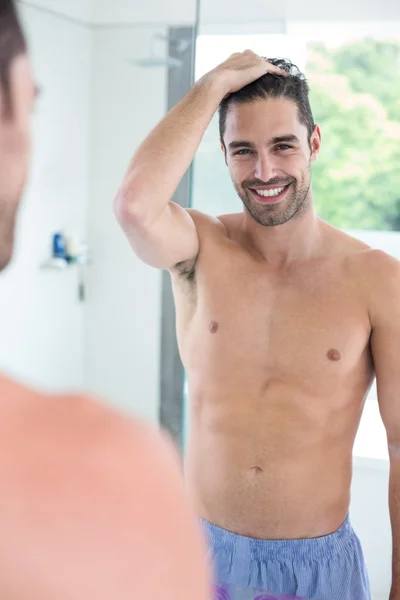 Hombre sonriendo mientras se mira en el espejo — Foto de Stock