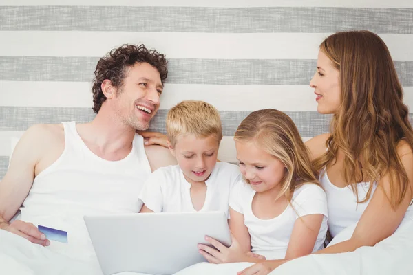 Famiglia con computer portatile sul letto — Foto Stock