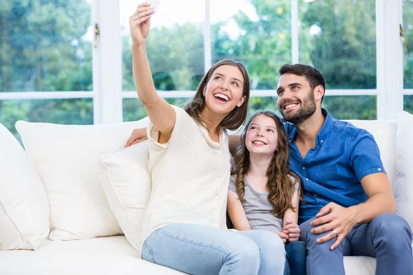 Família clicando selfies no sofá — Fotografia de Stock