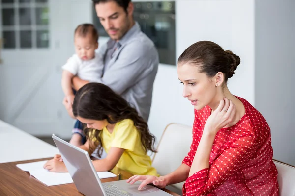 Madre che lavora su laptop con figlia che studia — Foto Stock