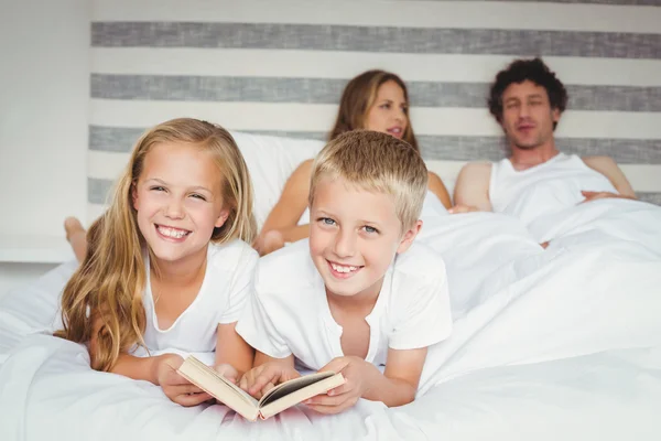 Hermanos relajándose con los padres en la cama — Foto de Stock