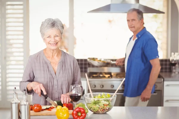 Woman cutting vegetables with husband — Stock Photo, Image