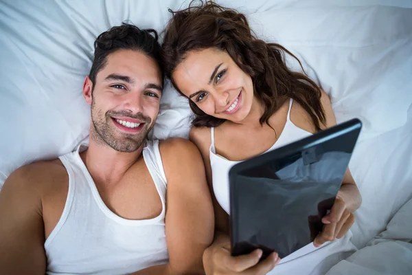 Pareja con tableta digital acostada en la cama — Foto de Stock