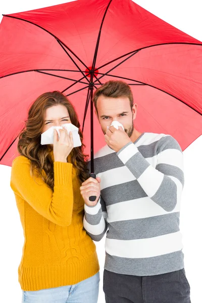 Couple holding umbrella and wiping nose — Stock Photo, Image