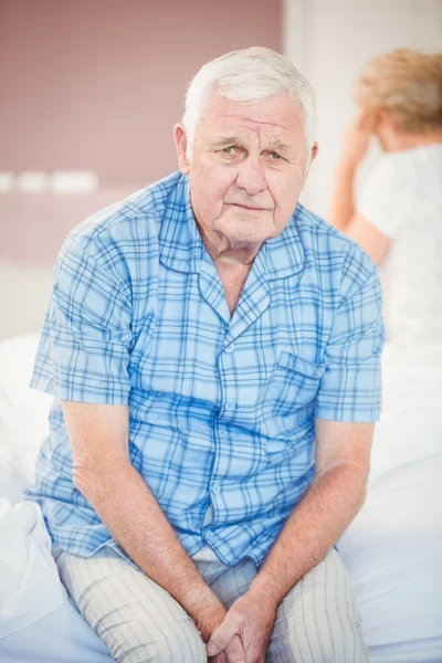 Uomo anziano teso seduto sul letto — Foto Stock