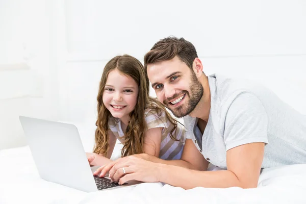 Pai e filha usando laptop na cama — Fotografia de Stock