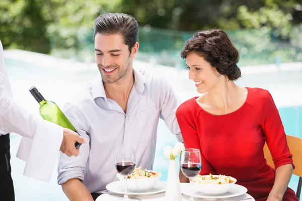 Garçom mostrando garrafa de vinho para casal — Fotografia de Stock