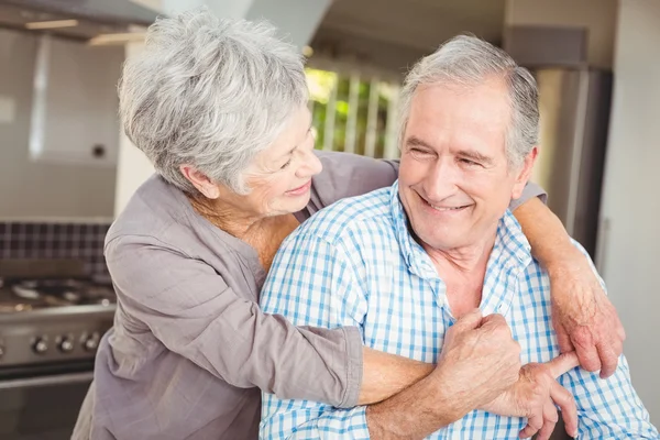 Веселая пожилая пара обнимается на кухне — стоковое фото