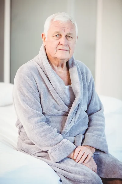 Starszy mężczyzna siedzi na łóżku — Zdjęcie stockowe