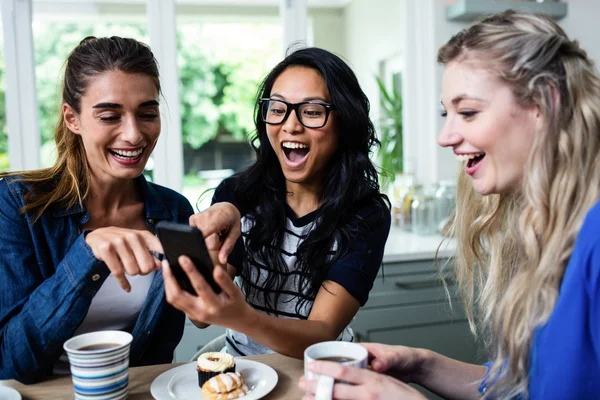 Freunde lachen, während sie auf das Telefon zeigen — Stockfoto