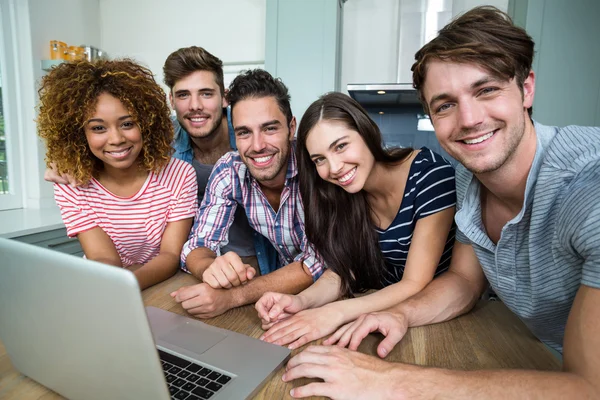 Amis souriant tout en utilisant un ordinateur portable sur la table — Photo