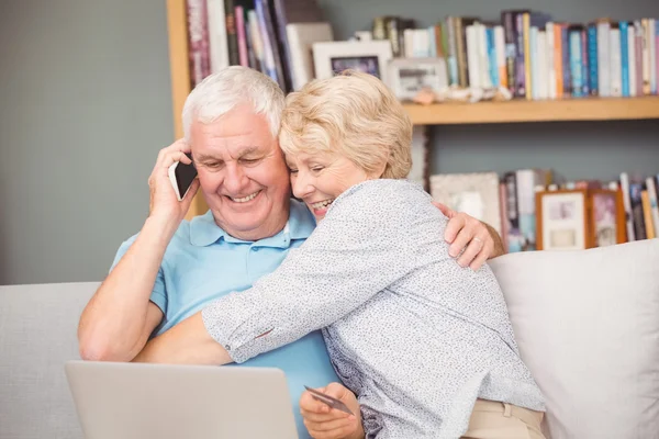 Woman hugging husband while using laptop — Stock Photo, Image