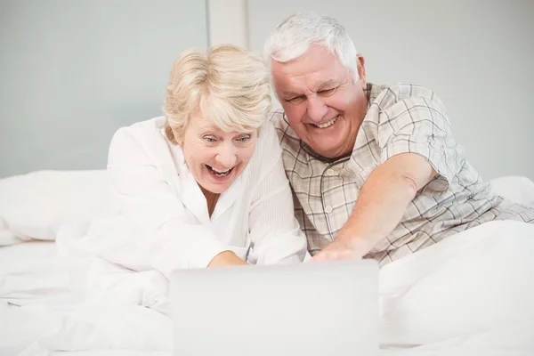 Pareja riendo mientras usa el portátil en la cama — Foto de Stock