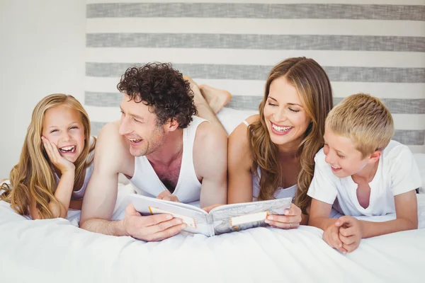 Family reading book on bed — Stock Photo, Image