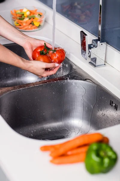 Woman washing tomatoes at kitchen washbasin — Stock Photo, Image