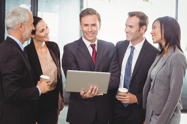 Geschäftsleute stehen mit Laptop zusammen — Stockfoto