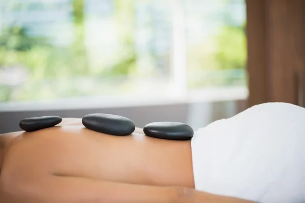 Mujer acostada con piedras en la espalda — Foto de Stock