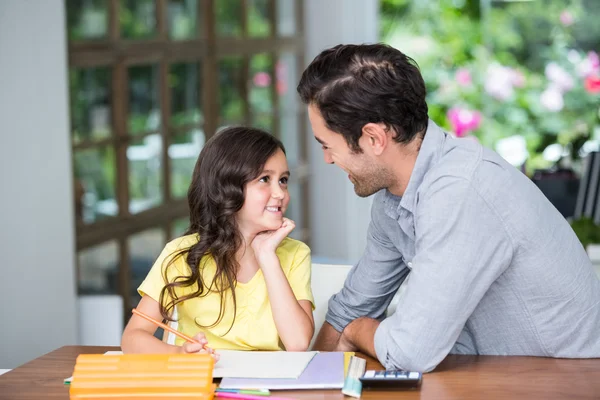 Усміхнений батько і дочка сидять за столом — стокове фото