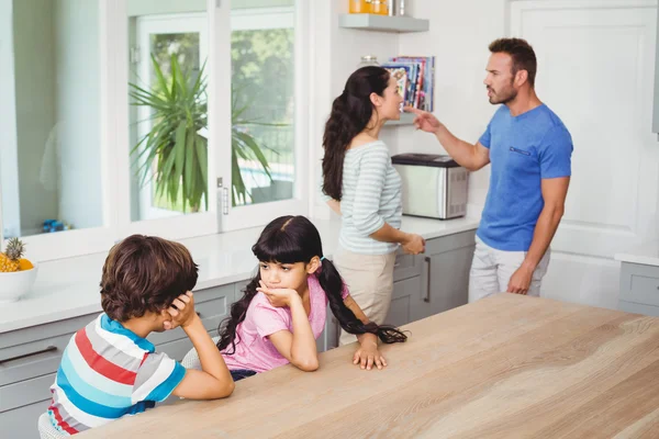 Kinder sitzen mit streitenden Eltern am Tisch — Stockfoto