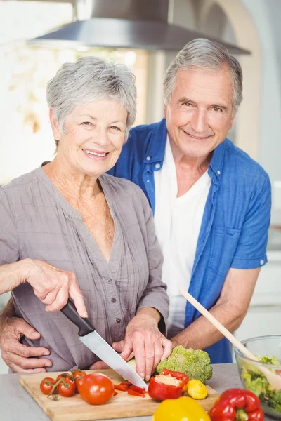 Woman cutting while man embracing in kitchen Royalty Free Stock Photos