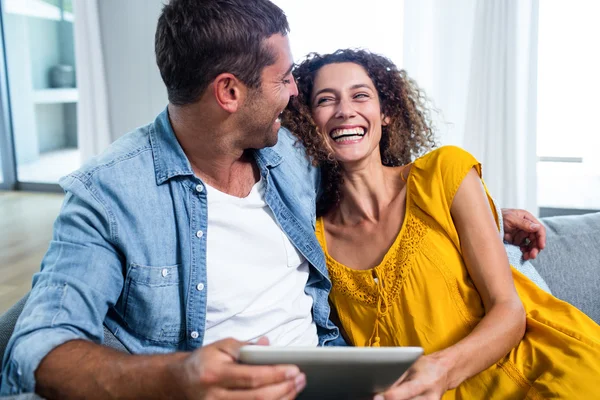 Casal feliz usando um tablet digital no sofá — Fotografia de Stock