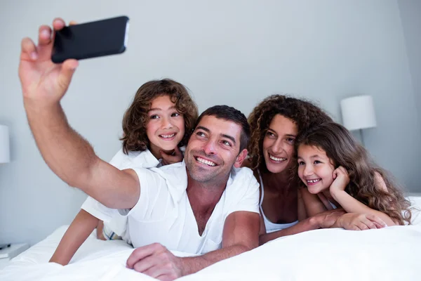 Famille heureuse prenant un selfie sur le lit — Photo