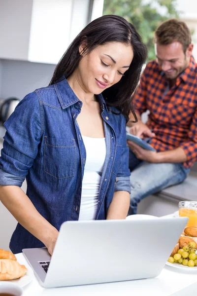 Cuplu folosind laptop și tabletă digitală în bucătărie — Fotografie, imagine de stoc