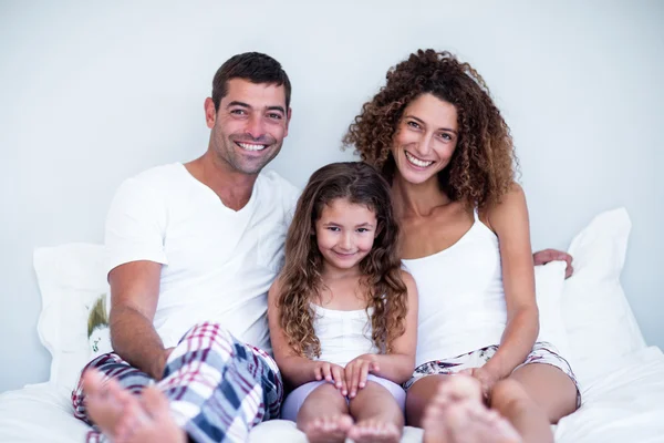 Portrait of a family sitting together on bed — Stock Photo, Image