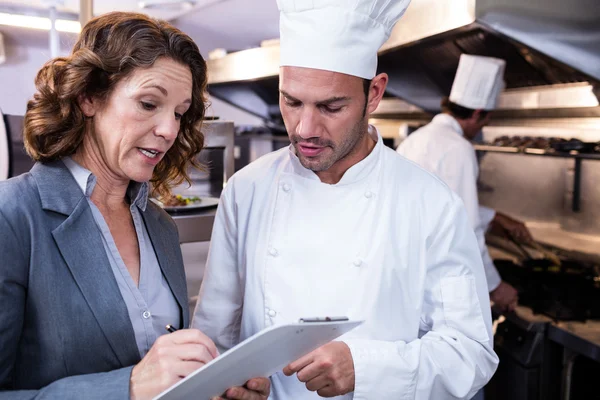 Restaurantleiter schreibt auf Klemmbrett — Stockfoto