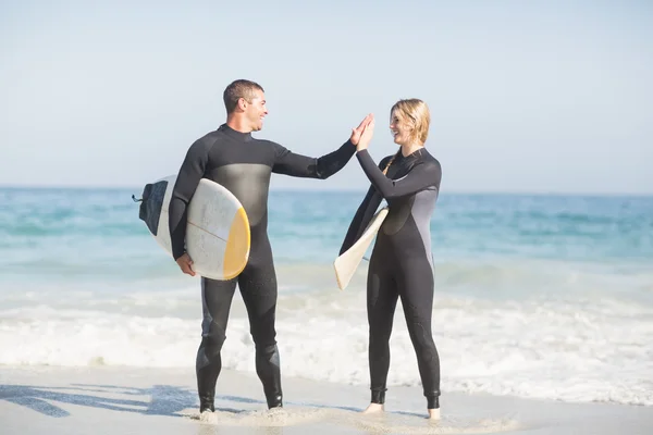 Pareja sosteniendo una tabla de surf — Foto de Stock