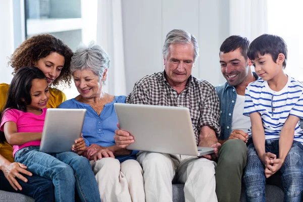 Famille heureuse utilisant ordinateur portable et tablette numérique dans le salon — Photo