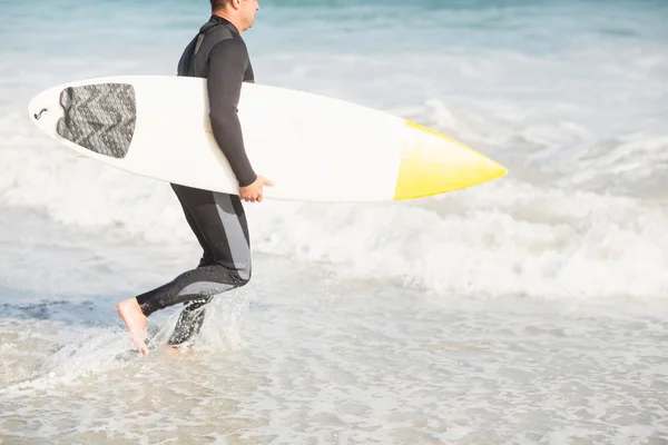 Sörfçü bir surfboard ile Sahilde yürüyüş — Stok fotoğraf