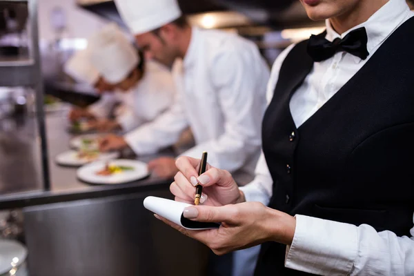 Waitress with note pad in commercial kitchen — Stock Photo, Image